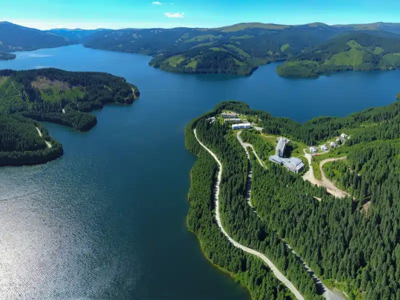 Blue lake surrounded by trees with a holiday resort on a peninsula