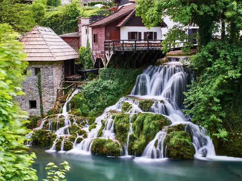 waterfall by a traditional wooden and stone building