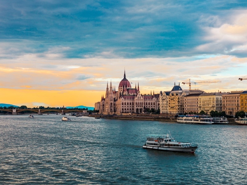 An image of the Danube river with the church on the banks and a bridge in the background