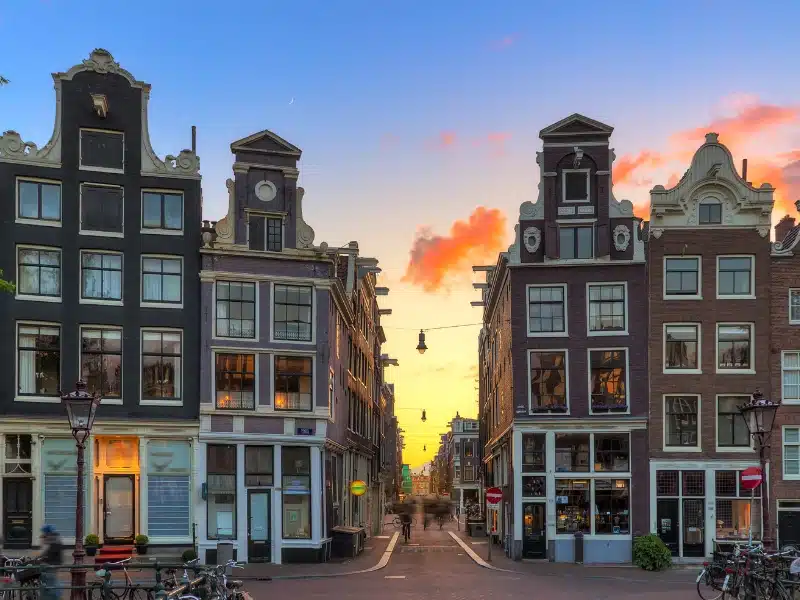 An image of the entrance to a street in Amsterdam with tall narrow buildings on either side