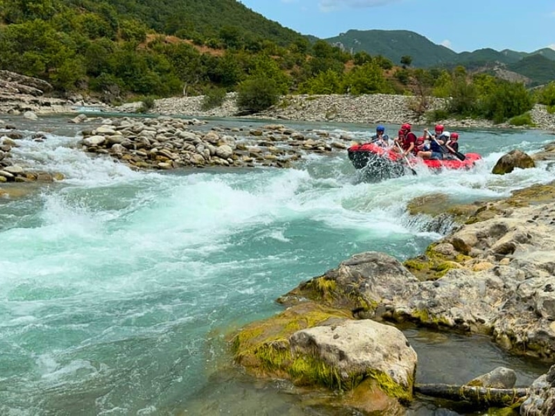 Red inflatable raft full of people on a white water section of a river
