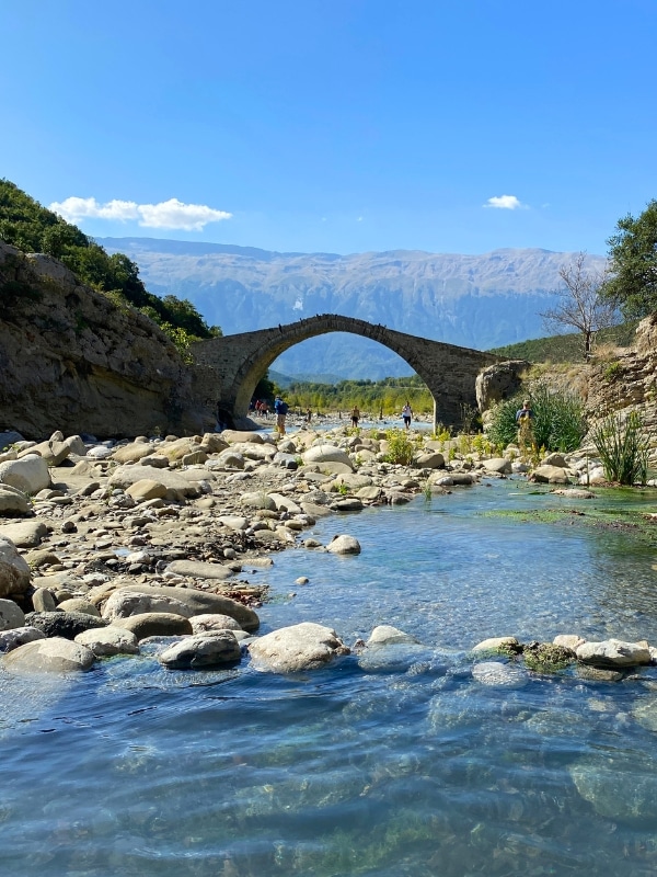 Arched stone bridge over a rocky river of clear water