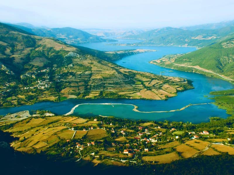 vibrant blue lake surrounded by green hills and fields