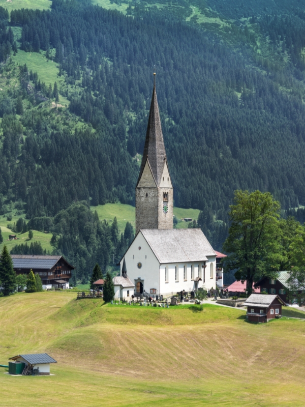 Mountain scenery with a small white church and stone tower