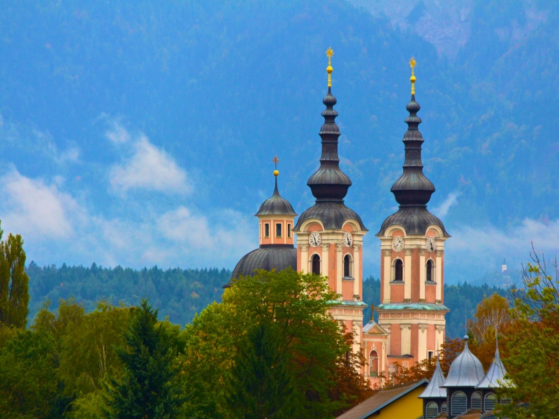 twin peach colored church towers seen through trees