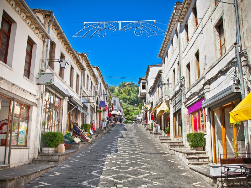 paved uphill street lined with colorful shops