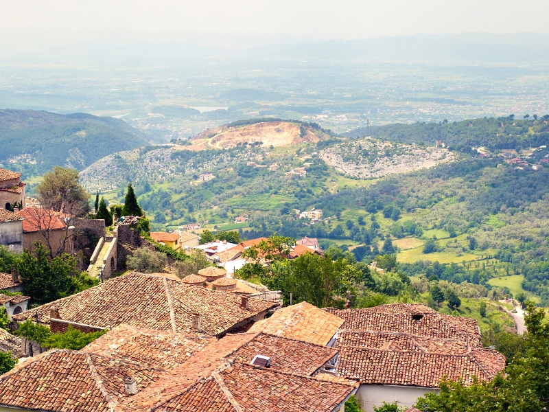 view across terracotta tiled roofs to a distant tree filled valley