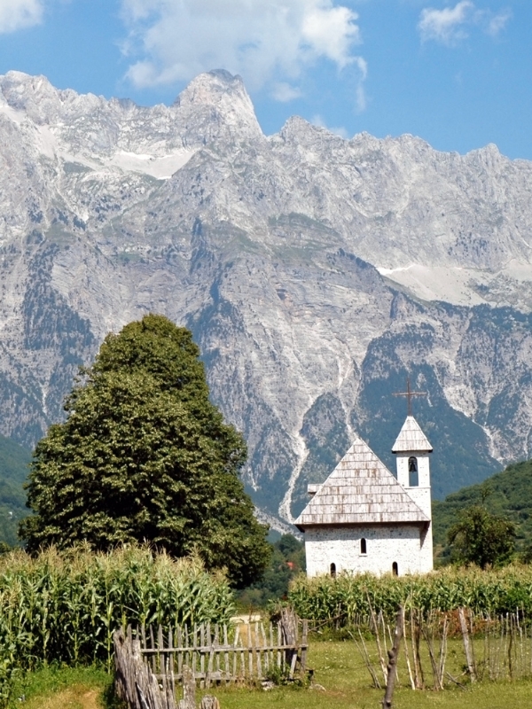 small church next to a chestnut tree with a large mountain backdrop