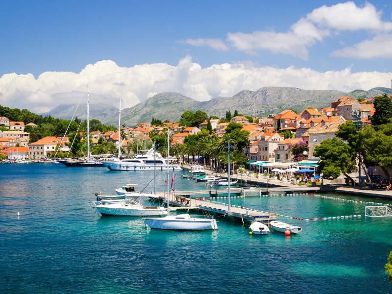 town with busy harbor full of yachts and mountains in the background