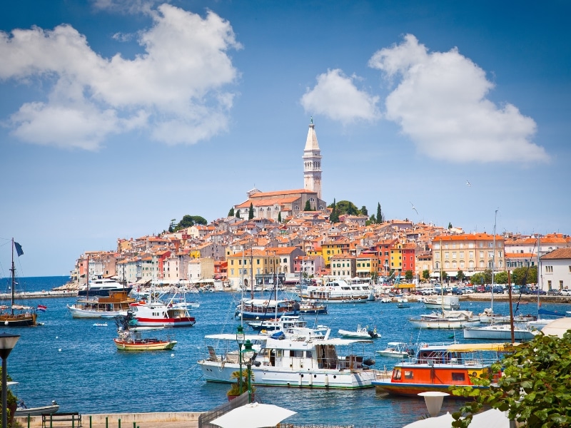 colorful town and harbor with tall church spire on a hill