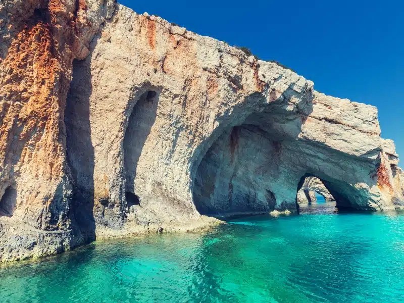 Series of rock arches above a clear turquoise green sea