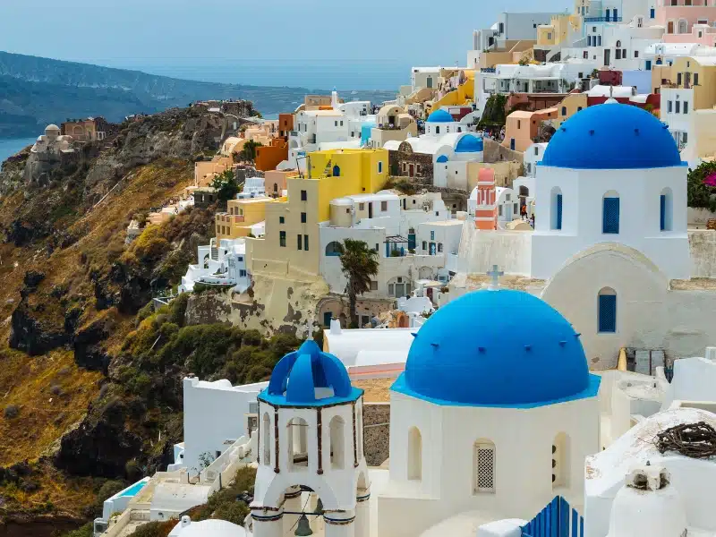 colorful houses and blue domed churches on a hillside