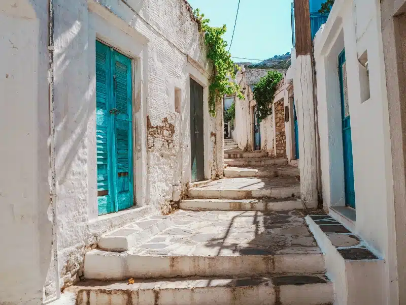 White houses on a stone lined street with turquoise doors and shutters