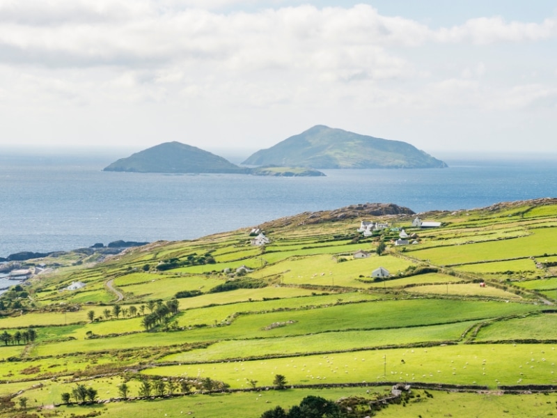 View across rolling green fields to two  conical shaped islands, one large one small