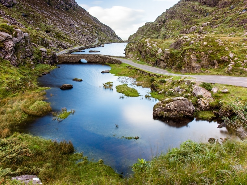 Road and stone bridge over a small lake