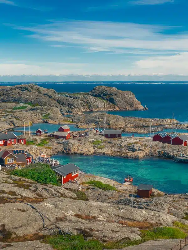 red houses built on a rocky shore by clear turquoise water