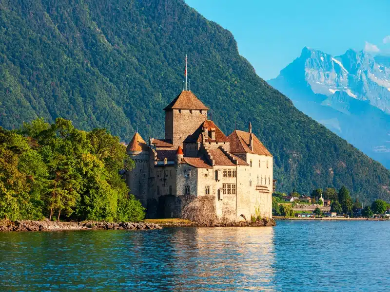 Lakeside castle with large mountains in background