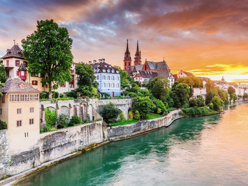 buildings and a twin spired cathedral along a river bank