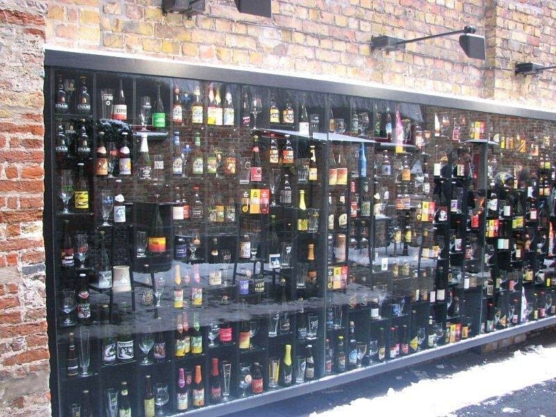 a wall of beer bottles and glasses on display