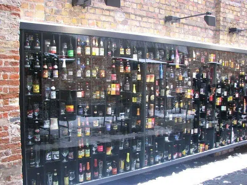 a wall of beer bottles and glasses on display