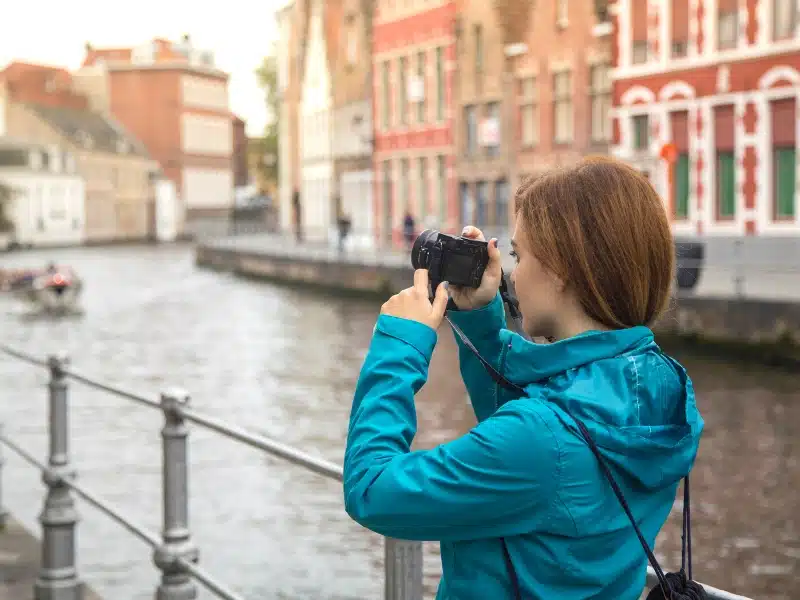 Woman taking a photograph on a camera by a canal