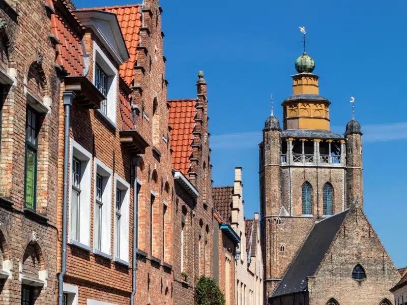 Square church tower with an octagonal top next to Dutch gabled houses