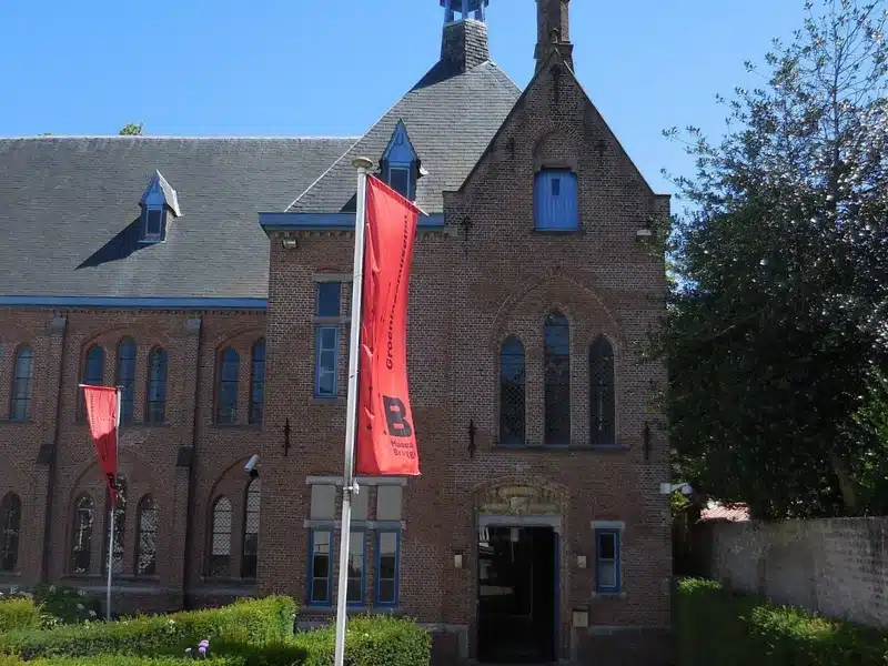 red brick building with church like windows and red flags flying in front