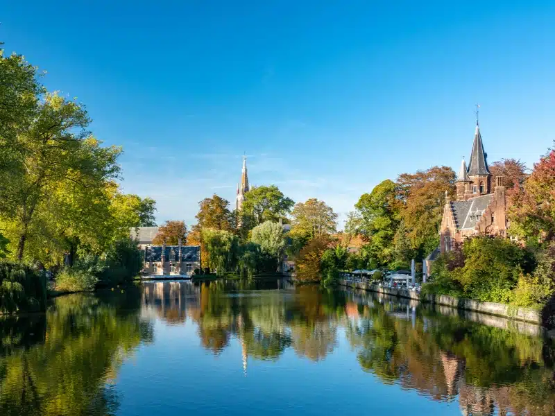 Mirror lake with trees and spired buildings in the shore