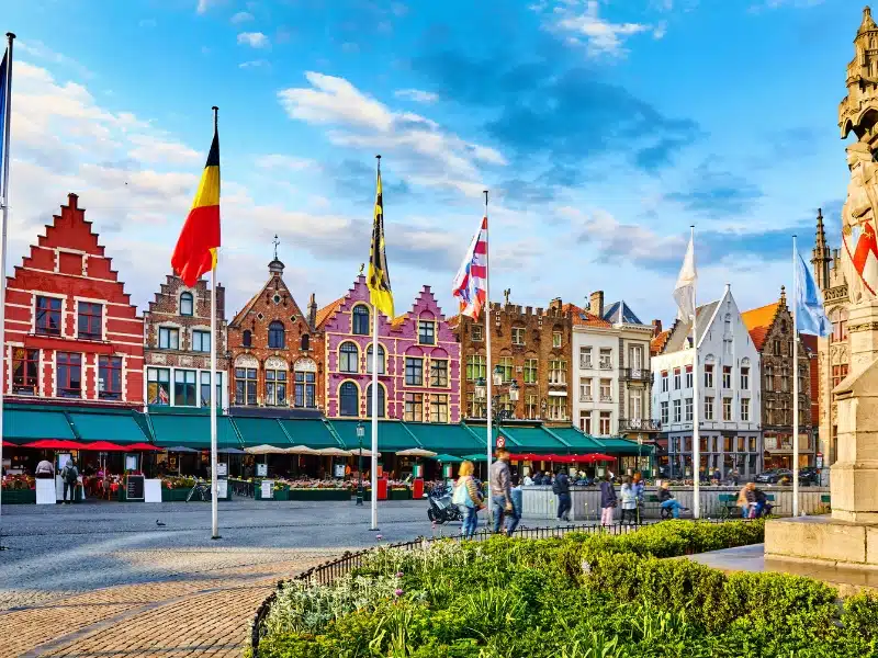 colorful gable end buildings with green canopy awnings in a square in Bruges