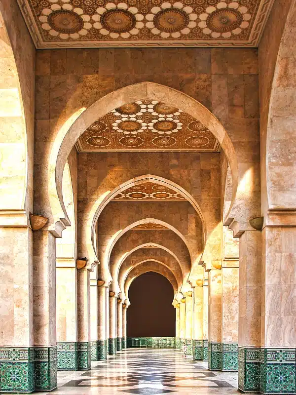 Huge corridor through Moroccan arches lined with marble and green coloured tiles