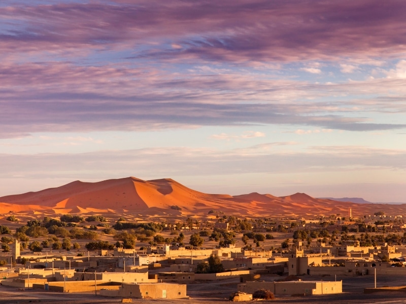 The rose red sand dunes of Erg Chebbi with the town of Merzouga in front