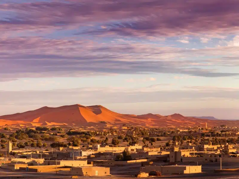 The rose red sand dunes of Erg Chebbi with the town of Merzouga in front