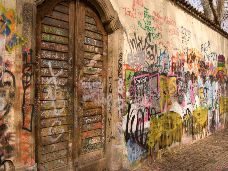 An image of a Graffitied wall with a set of all medieval doors