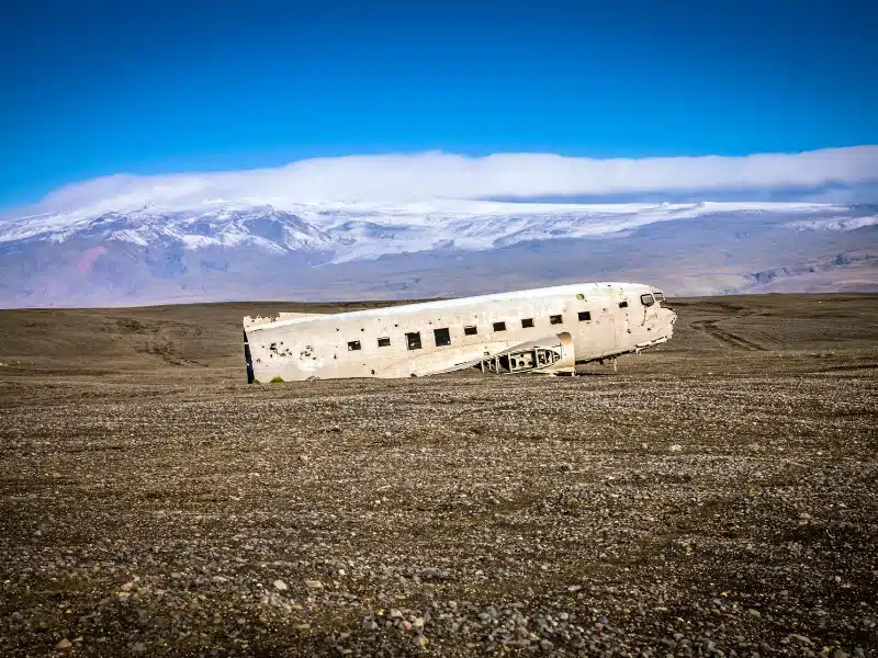 Wrecked plane on black pebbly field