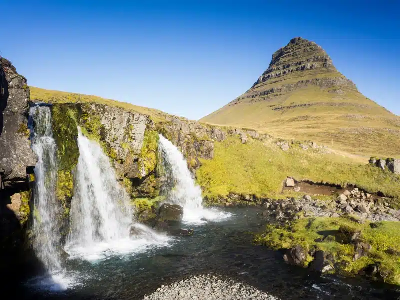three waterfalls by conical shaped grassy mountain