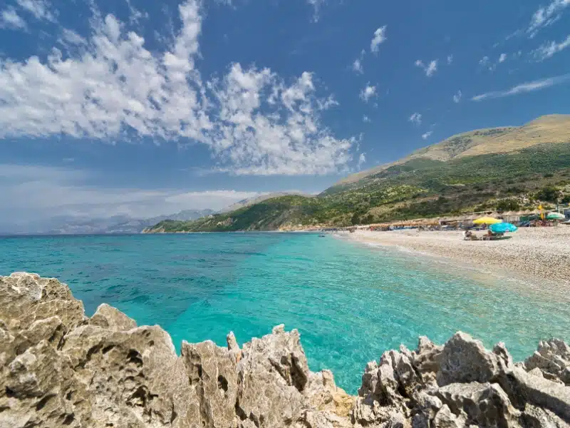 Turqoise sea and a sandy beach with yellow and turquoise beach umberellas