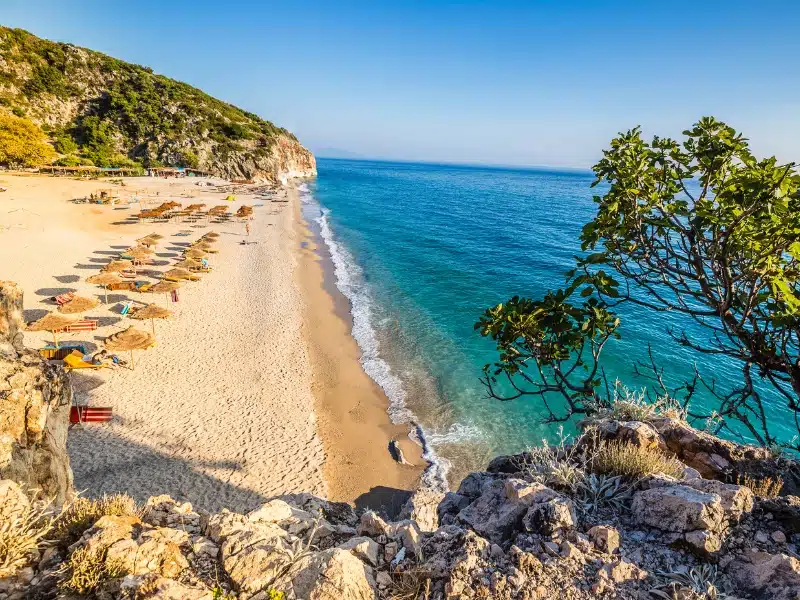 Sandy beach backed by grassy cliffs with a turquoise sea