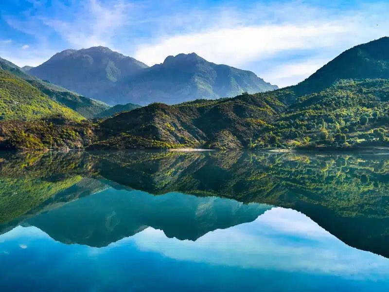 mirror lake surrounded by hills with mountains in the background