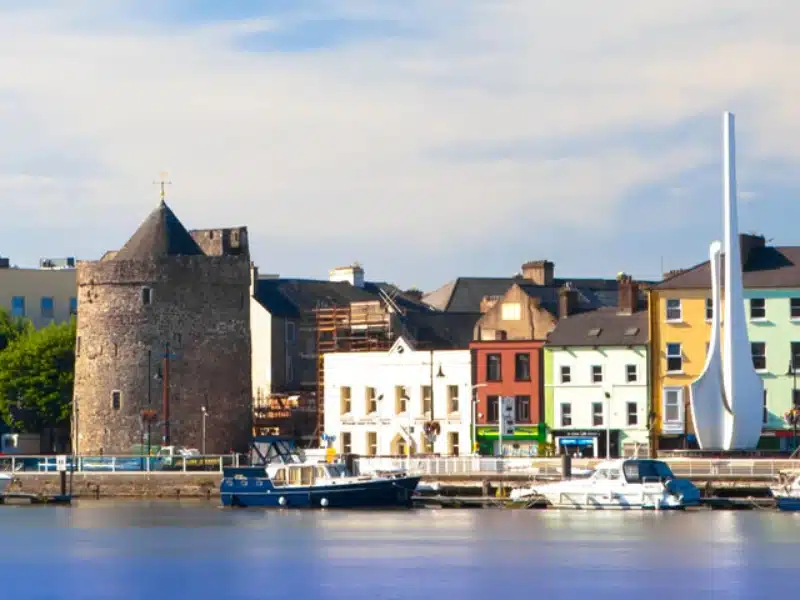 round stone tower on a quay with buildings and boats