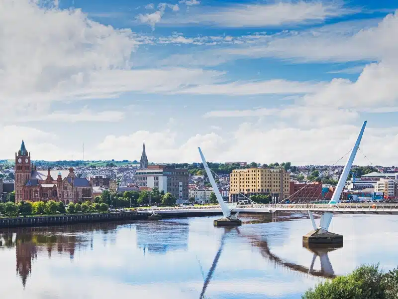 modern bridge over a river with historic buildings on the far side