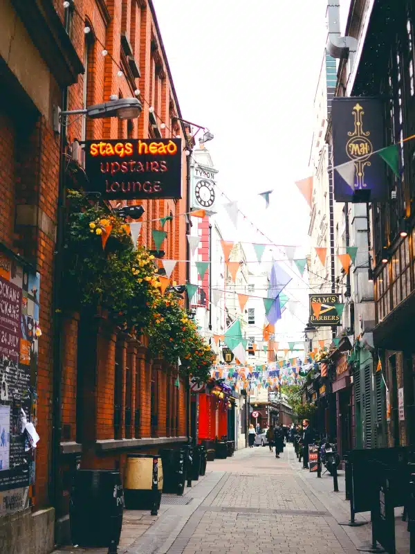 orange green and white flags hanging above a street lined with pubs