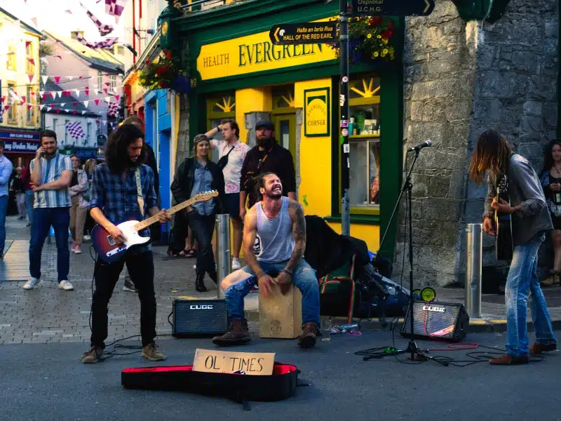 people playing instruments in a street outside a green and yellow shop front