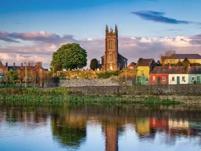 small church with a square tower nest to old houses on a waterfront