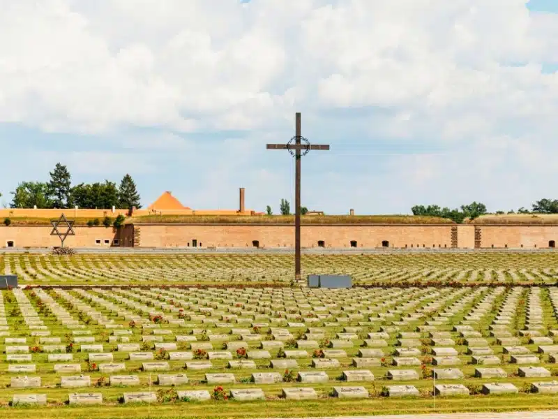 grave markets in a ex concentration camp with a cross in the middle of the burial field.