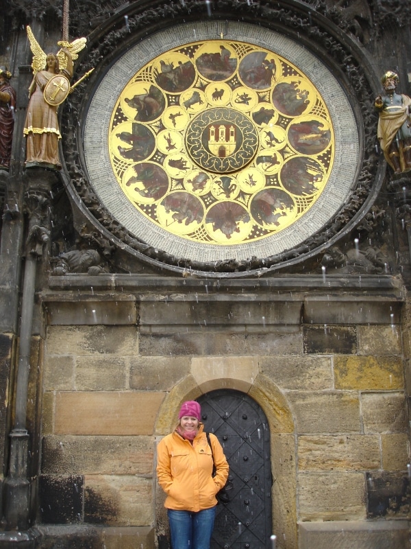 Part of the astronomical closk in Prague with a woman in an orange coat and pink hat standing underneath