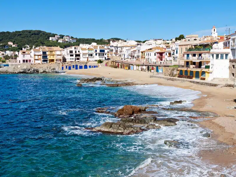 sandy and rocky cove with a colorful village behind the beach