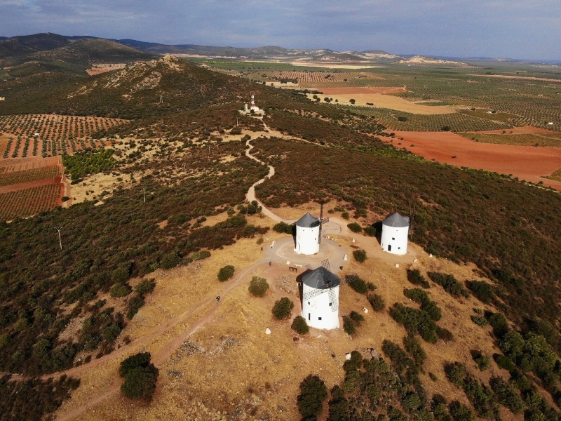 three white windmills with conical roofs on a ridge with an agricultural landscape in the background