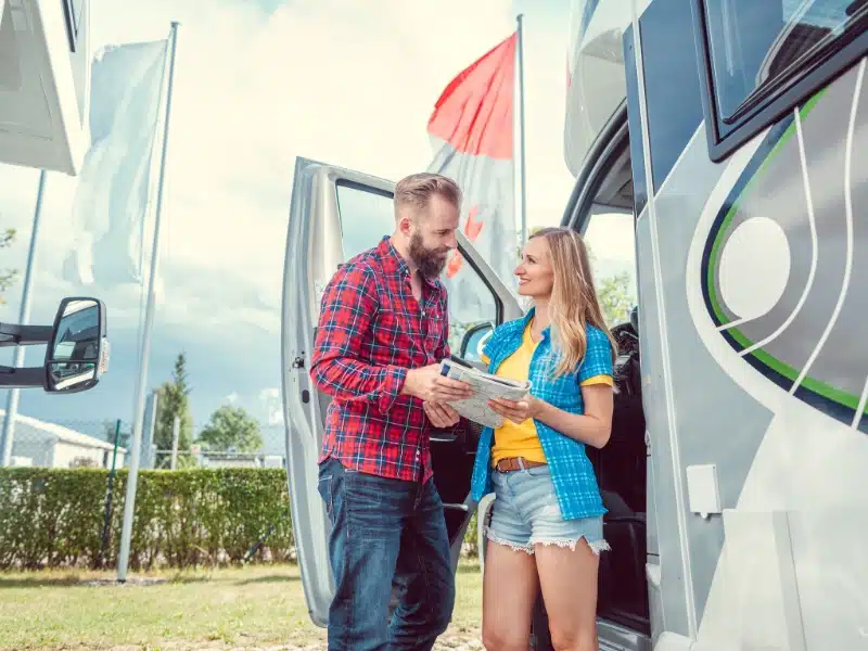 man and a woman by a motorhome looking at documentation