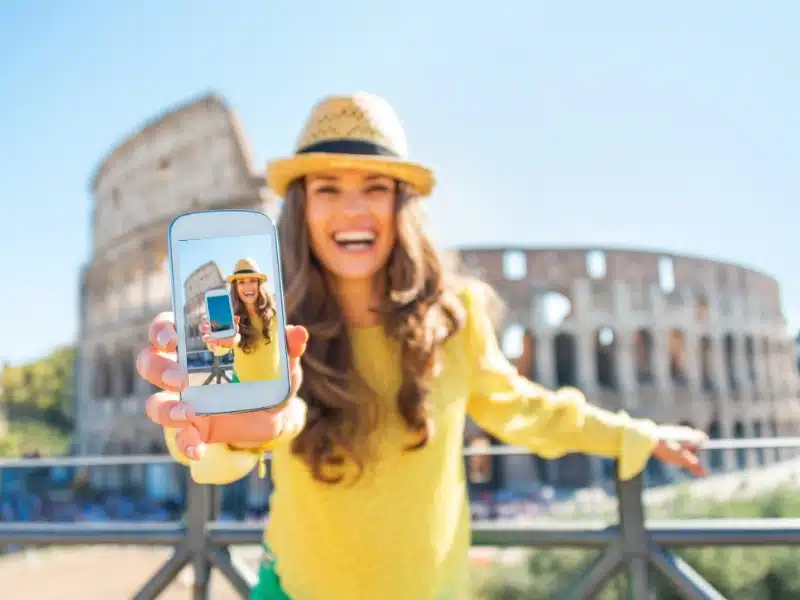 person holding phone in from of the Colosseum in Rome
