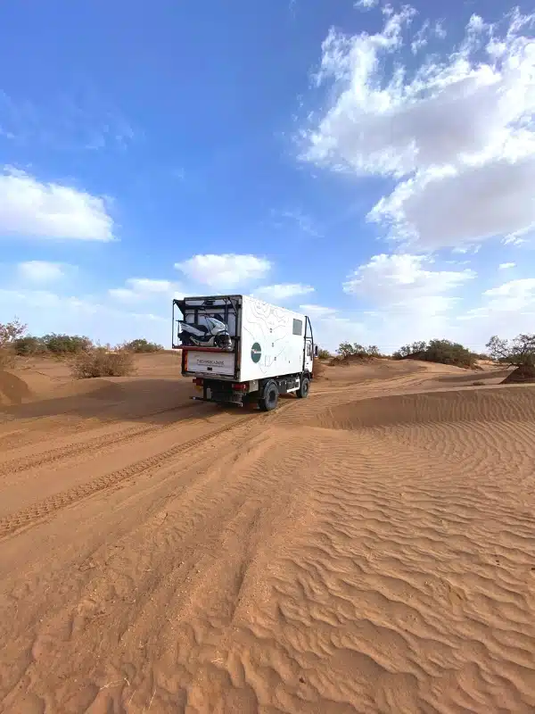 white truck driving through the sandy desert